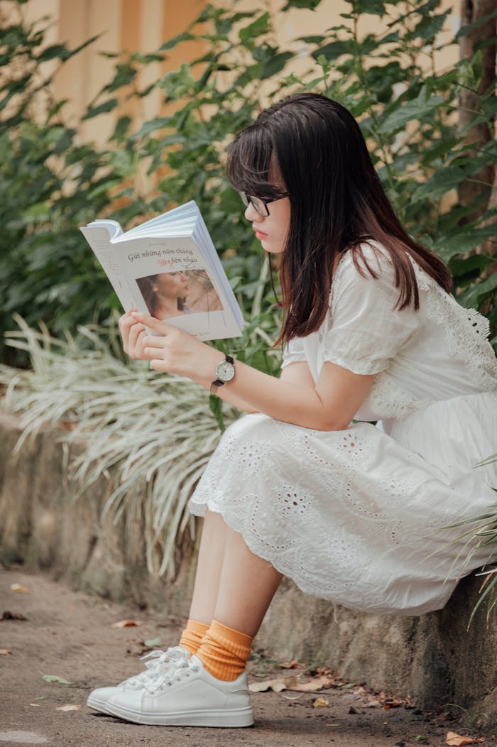 services-02 Asian woman in dress reading a book outdoors, enjoying a summer day.